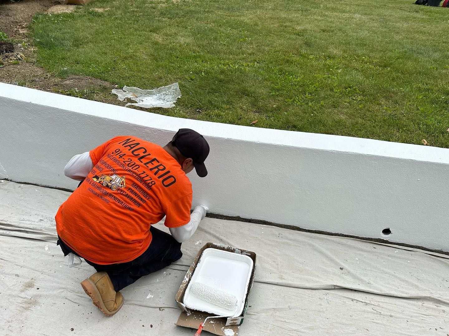 Naclerio Construction worker applying waterproofing to a Westchester County foundation
